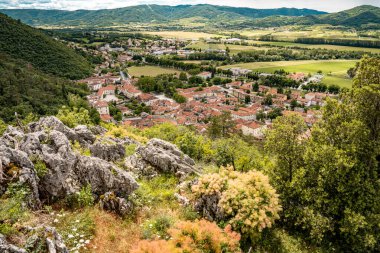 Kale Harabelerinden Vipava 'nın Resimli Manzarası: Kırmızılı Çatı ve Kilise Kulesi Önplanda Çiçek Açan Çiçekler ve Arka planda Yuvarlanan Tarlalar, Slovenya. 