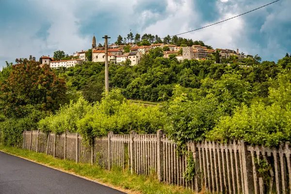 Slovenya 'nın Manzaralı Tepe Kenti Stanjel: Karst Bölgesi' nde Geleneksel Taş Evler ve Çiçek Yeşiller Altında Yükselen Tarihi Kilise Kulesi. Yüksek kalite fotoğraf