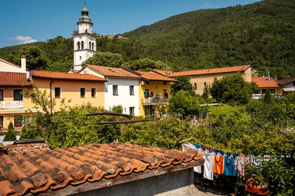 Vipava 'nın Kale Manzaralı Büyüleyici Kasabası: Batı Slovenya' da Açık Mavi Gökyüzü Altında Uzak Kale Harabeleri Olan Renkli Tarihi Evler ve Kilise Kulesi