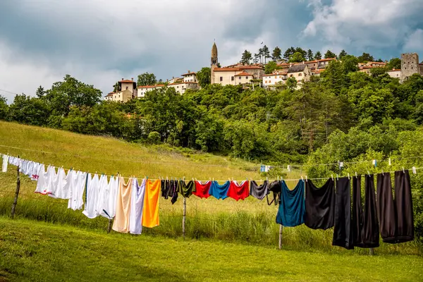 Slovenya 'nın Manzaralı Tepe Kenti Stanjel: Karst Bölgesi' nde Geleneksel Taş Evler ve Çiçek Yeşiller Altında Yükselen Tarihi Kilise Kulesi. Yüksek kalite fotoğraf