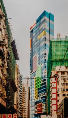 Hong Kong 'daki yoğun yüksek binalar: Dünyanın en kalabalık şehirlerinden birinde, bulutlu bir gökyüzü altında, modern apartmanların katmanlarıyla yükselen şehir silueti. Yüksek kalite fotoğraf