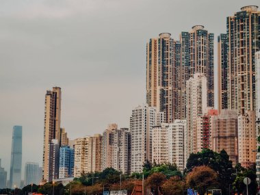 Hong Kong 'daki yoğun yüksek binalar: Dünyanın en kalabalık şehirlerinden birinde, bulutlu bir gökyüzü altında, modern apartmanların katmanlarıyla yükselen şehir silueti. Yüksek kalite fotoğraf
