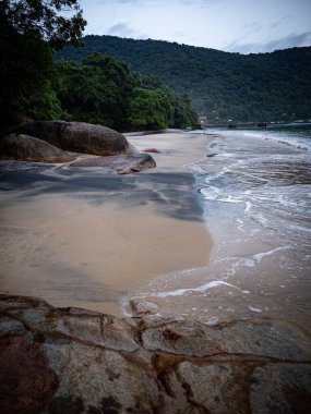 Rio De Janeiro yakınlarındaki Ilha Grande 'de Huzurlu Plaj: Kibar Dalgalar Rocky Outcrops ile Sandy Shore' a vuruyor ve Tropikal Brezilya Cennetindeki yemyeşil tepeler. Yüksek kalite fotoğraf