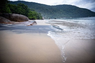 Rio De Janeiro yakınlarındaki Ilha Grande 'de Huzurlu Plaj: Kibar Dalgalar Rocky Outcrops ile Sandy Shore' a vuruyor ve Tropikal Brezilya Cennetindeki yemyeşil tepeler. Yüksek kalite fotoğraf
