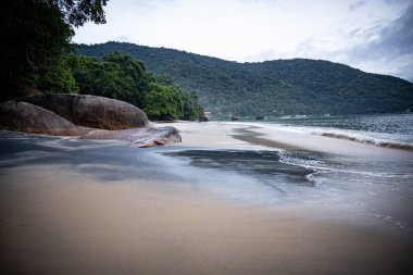 Rio De Janeiro yakınlarındaki Ilha Grande 'de Huzurlu Plaj: Kibar Dalgalar Rocky Outcrops ile Sandy Shore' a vuruyor ve Tropikal Brezilya Cennetindeki yemyeşil tepeler. Yüksek kalite fotoğraf