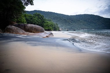Rio De Janeiro yakınlarındaki Ilha Grande 'de Huzurlu Plaj: Kibar Dalgalar Rocky Outcrops ile Sandy Shore' a vuruyor ve Tropikal Brezilya Cennetindeki yemyeşil tepeler. Yüksek kalite fotoğraf