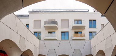 Freiham Münih Bavyera 'daki Modern Mimari: Geometrik Yüzlü Minimalist Bina, Büyük Pencereler, Kavisli Kemer Detayları ve Bulutlu Gök Altındaki Küçük Ağaç. Yüksek kalite fotoğraf