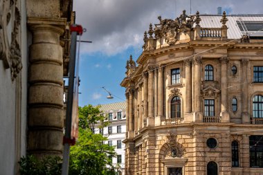 Münih 'teki Barok Mimari: Heykel Yüzlü Süslü Tarihi Bina, Kemerli Pencereler, Dekoratif Sütunlar ve Mavi Gökyüzü Altında Bulutlu Taş Detayları. Yüksek kalite fotoğraf