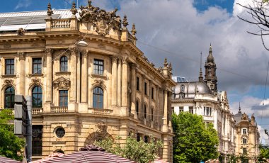 Münih 'teki Barok Mimari: Heykel Yüzlü Süslü Tarihi Bina, Kemerli Pencereler, Dekoratif Sütunlar ve Mavi Gökyüzü Altında Bulutlu Taş Detayları. Yüksek kalite fotoğraf