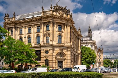 Münih 'teki Barok Mimari: Heykel Yüzlü Süslü Tarihi Bina, Kemerli Pencereler, Dekoratif Sütunlar ve Mavi Gökyüzü Altında Bulutlu Taş Detayları. Yüksek kalite fotoğraf