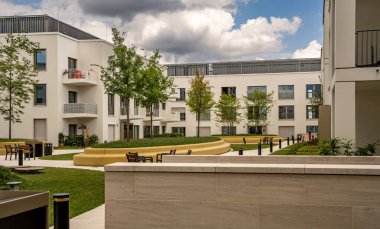 Freiham Münih Bavyera 'daki Modern Mimari: Geometrik cepheli Minimalist Bina, Büyük Pencereler ve Bulutlu Gök Altındaki Küçük Ağaç. Yüksek kalite fotoğraf