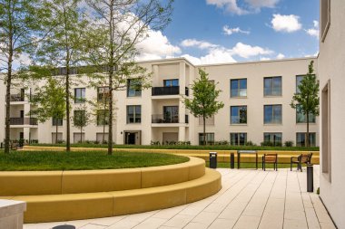 Freiham Münih Bavyera 'daki Modern Mimari: Geometrik cepheli Minimalist Bina, Büyük Pencereler ve Bulutlu Gök Altındaki Küçük Ağaç. Yüksek kalite fotoğraf