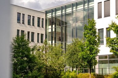 Freiham Münih Bavyera 'daki Modern Mimari: Geometrik cepheli Minimalist Bina, Büyük Pencereler ve Bulutlu Gök Altındaki Küçük Ağaç. Yüksek kalite fotoğraf