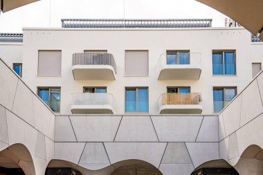 Freiham Münih Bavyera 'daki Modern Mimari: Geometrik Yüzlü Minimalist Bina, Büyük Pencereler, Kavisli Kemer Detayları ve Bulutlu Gök Altındaki Küçük Ağaç. Yüksek kalite fotoğraf