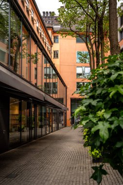 Modern Sokak Sahnesi Münih Merkezi: Sessiz bir şehir avlusunda cam cepheli ve yeşillikli çağdaş mimari. Yüksek kalite fotoğraf