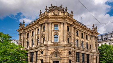 Münih 'teki Barok Mimari: Heykel Yüzlü Süslü Tarihi Bina, Kemerli Pencereler, Dekoratif Sütunlar ve Mavi Gökyüzü Altında Bulutlu Taş Detayları. Yüksek kalite fotoğraf