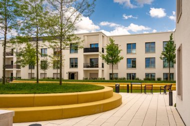 Freiham Münih Bavyera 'daki Modern Mimari: Geometrik cepheli Minimalist Bina, Büyük Pencereler ve Bulutlu Gök Altındaki Küçük Ağaç. Yüksek kalite fotoğraf