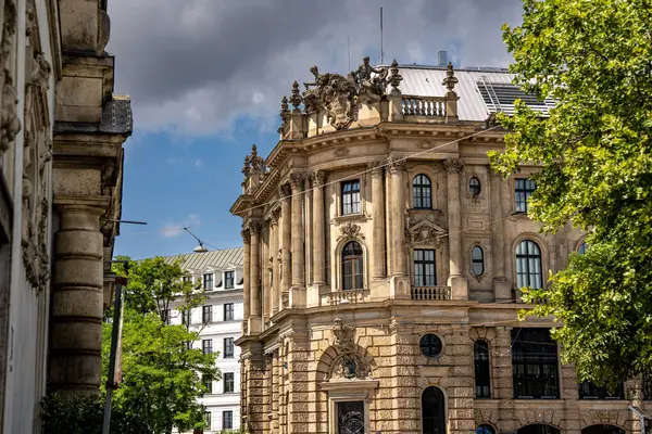 Münih 'teki Barok Mimari: Heykel Yüzlü Süslü Tarihi Bina, Kemerli Pencereler, Dekoratif Sütunlar ve Mavi Gökyüzü Altında Bulutlu Taş Detayları. Yüksek kalite fotoğraf