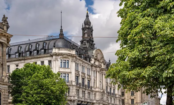 Münih 'teki Barok Mimari: Heykel Yüzlü Süslü Tarihi Bina, Kemerli Pencereler, Dekoratif Sütunlar ve Mavi Gökyüzü Altında Bulutlu Taş Detayları. Yüksek kalite fotoğraf