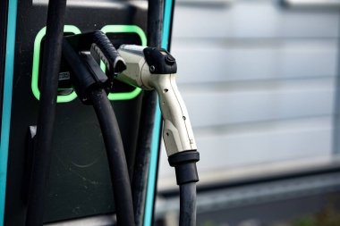 Çift bağlantıları olan elektrikli araç şarj istasyonu: Modern EV güç tedarik kablolarına yakın çekim ve şehir merkezinde üzerinde yeşil LED çizgileri olan prizler. Yüksek kalite fotoğraf