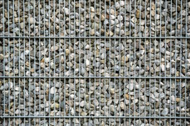 Küçük doğal taşlarla dolu metal tel örgülerin yakın görüntüsü desenli ve endüstriyel arka plan yüzeyi oluşturuyor. Yüksek kalite fotoğraf