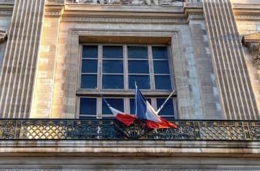 Geniş pencereli ve Fransız bayraklı bir binanın ön cephesi. Paris, Fransa