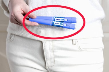 Beyaz elbiseli kadın elinde kırmızı yuvarlak çizgili mavi bir Ozempic enjeksiyon kalemi tutuyor. Kopenhag, Danimarka - 24 Nisan 2025 