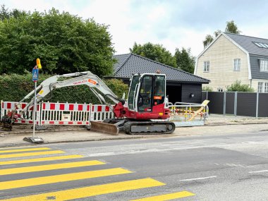 Küçük bir buldozer sokakta bir çukur kazdı. Kopenhag, Danimarka - 23 Temmuz 2025