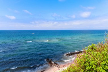 Kıyı şeridi kayalık dalgalı ve mavi gökyüzü bulutlu 