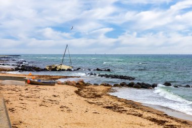 Sarı kumlu kıyı şeridi uzanıyor, uzak yatlar kırık ve sessiz.. 
