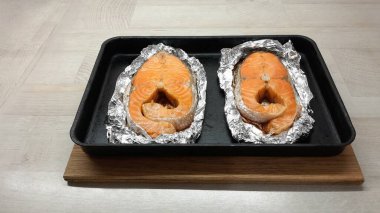 baked red fish steak, salmon baked in foil, fish steak on the table, salmon with spices 