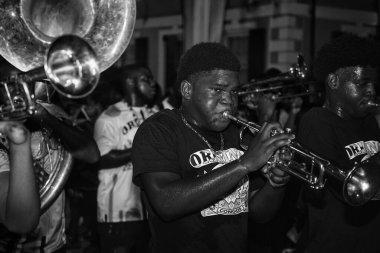 Canlı bir Junkanoo sokak sanatçısı, gece canlı bir geçit törenine katılan parlak, cesur giysiler içindeki bir müzisyeni yakalıyor.