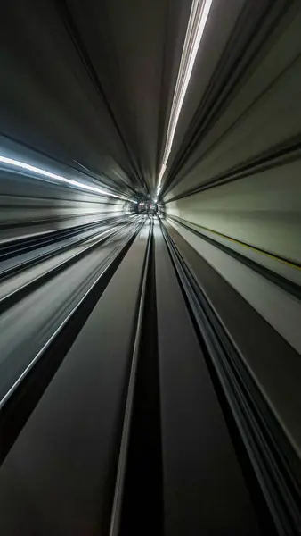 Fütürist bir tünelde hız ve hareket duygusunu yakalayan çarpıcı soyut bir görüntü. Dinamik çizgiler ve ışıklandırma hızlandırılmış bir hareket atmosferi yaratarak, yoğun geçiş ve modernlik duyguları uyandırıyor..