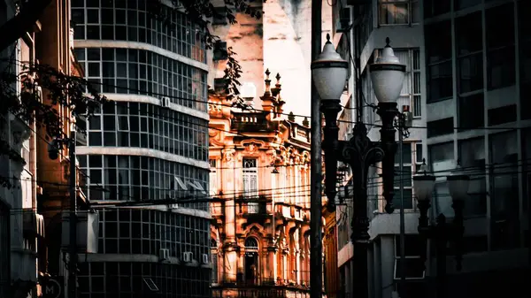 Şehir manzarası, modern gökdelenler arasında yer alan güzel tarihi bir bina, öğleden sonra güneşiyle aydınlanıyor, kentsel mimaride geçmiş ve şimdiki zamanın birleşimini simgeliyor..