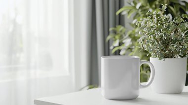 Parlak odadaki saksı bitkisinin yanındaki masada beyaz kupa.