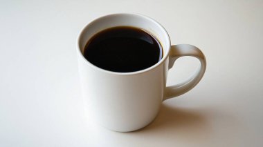 Temiz yüzeyde koyu kahveyle doldurulmuş beyaz kahve fincanı..