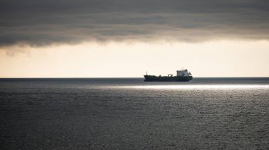 Gün batımında bir petrol tankerinin silueti Milford Haven, Pembrokeshire, Galler 'e yanaşmak için kuyruğa giriyor.