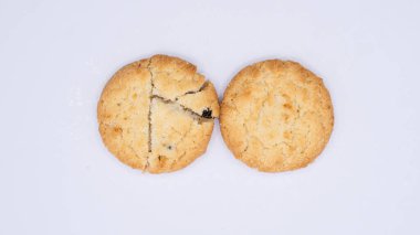 Göze çarpan koyu benekli, yuvarlak, altın sarısı kurabiyeler, muhtemelen çikolata parçacıkları ya da diğer karışımlar, düz beyaz bir yüzeyde dinleniyorlar. Biraz kırsal görünüşleri ve görünen dokuları ev yapımı ya da zanaatkar bir kaliteye işaret ediyor. Bu resim de öyle.