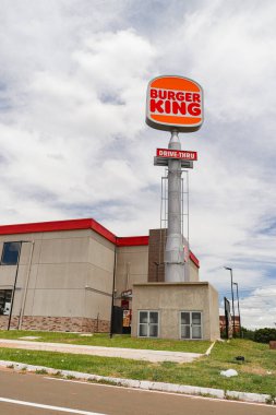 Bulutlu bir gökyüzünde turuncu ve kırmızı tuğlalı bir kulenin dikey görüntüsü