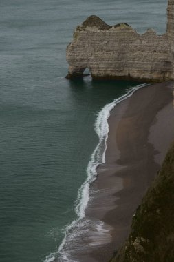 Etretat tebeşir kayalıkları sakin bir kış gökyüzünün ve sakin bir denizin zemininde dururlar..