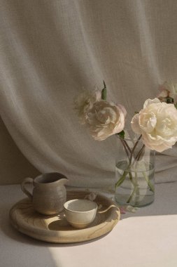 Fotoğraf, çerçevenin köşesine yerleştirilmiş dört beyaz gülden oluşan bir vazoyla ahşap bir tepside iki el yapımı çay fincanı yakalıyor. Yüksekliği 20 cm 'yi geçmeyen güller, daha da incelik katıyor.
