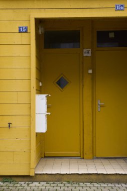 Parlak sarı kapıları ve şık posta kutusu tasarımları olan şık bir giriş, çağdaş evler için mükemmel..