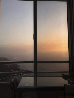 Göz kamaştırıcı bir gün batımı manzarası. Yüksek bir pencereden, sıcak renkler ve huzurlu bir hava.