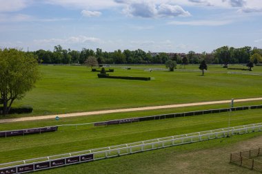 Wroclaw, Poland- Maj 3, 2024: Güneşli bir günde tarihi şehir hipodromunda yeşil çimenli, beyaz çitli yeşil bir at yarış pistinin manzarası. Spor, eğlence ve açık araziler.