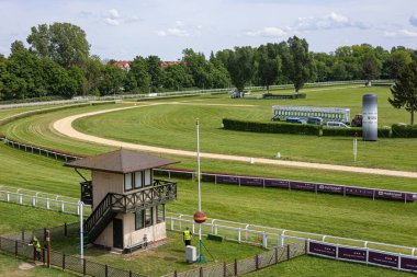 Wroclaw, Poland- Maj 3, 2024: Güneşli bir günde Wroclaw 'da modern bir hipodromda yarış pistinin başlangıç kapıları, kontrol kulesi ve yeşil çim tarlası manzarası. Binicilik sporları, at yarışı etkinlikleri ve açık hava eğlencesi.