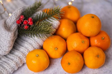 Yumuşak bir zemin üzerinde sıcak peri ışıklarıyla sıcak örülü eşarp, kırmızı böğürtlen ve yeşil çam dalları bulunan taze mandallar. Kış, tatiller ve mevsimlik atmosferler