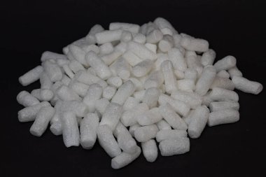 Yakın plan beyaz polistiren köpük yığını. Koyu arka planda fıstık paketleme, nakliye sırasında eşyaları yastık altına almak ve korumak için ideal. Hafif, eko-bilinçli ve verimli ambalaj çözümleri