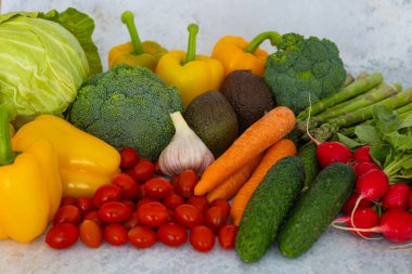Brokoli, sarı dolma biber, lahana, havuç, turp, salatalık, kiraz domatesleri, kuşkonmaz, avokado ve sarımsak da dahil olmak üzere renkli taze sebzeler. Sağlıklı ve doğal ürünler