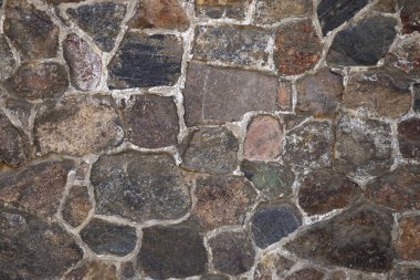 Close-up of a rustic stone wall with irregular shapes and natural texture in daylight. Concept of architecture, construction, and outdoor background clipart