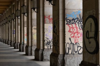 Wroclaw, Polonya-Marth 30, 2025: Renkli graffitilerle kaplı bir dizi taş kolon ile şehir koridoru, klasik mimari ve modern sokak sanatı arasında bir zıtlık yarattı